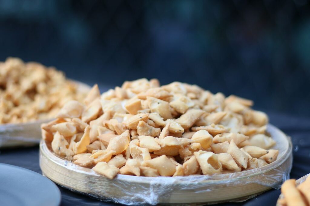 Close-up of a traditional Bangladeshi snack, crispy chira, served on a tray outdoors.