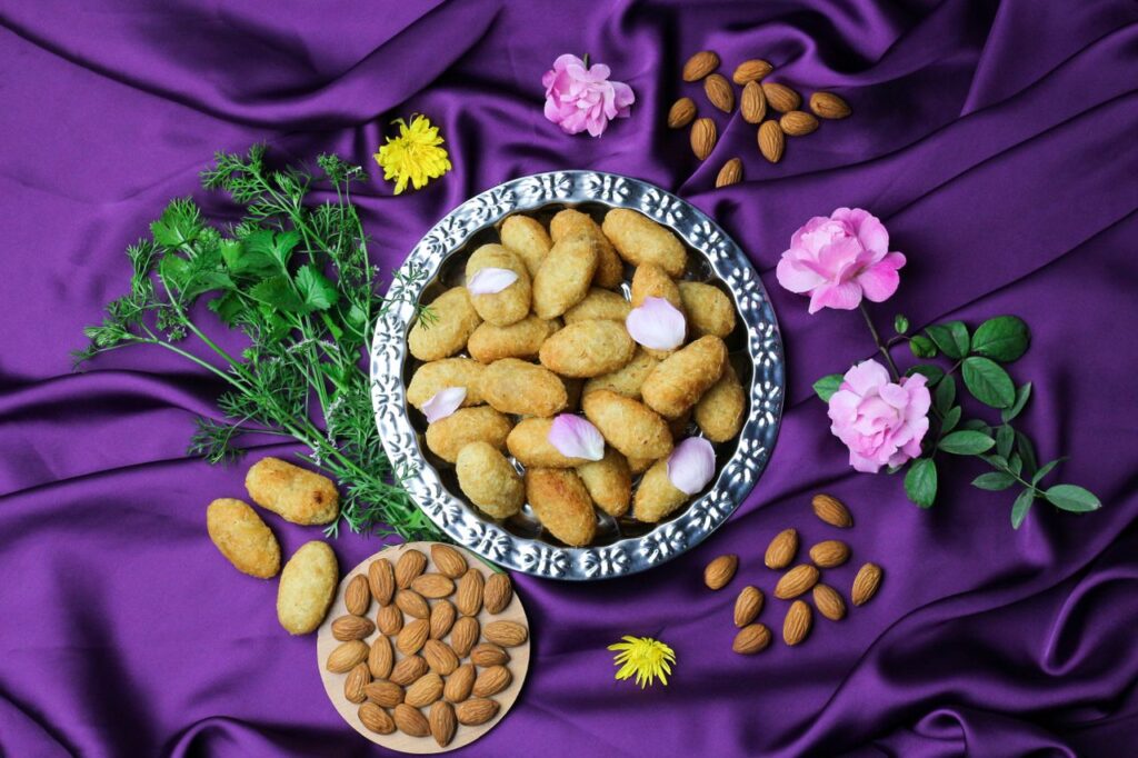 Overhead shot of croquettes and almonds garnished with flowers on purple silk.