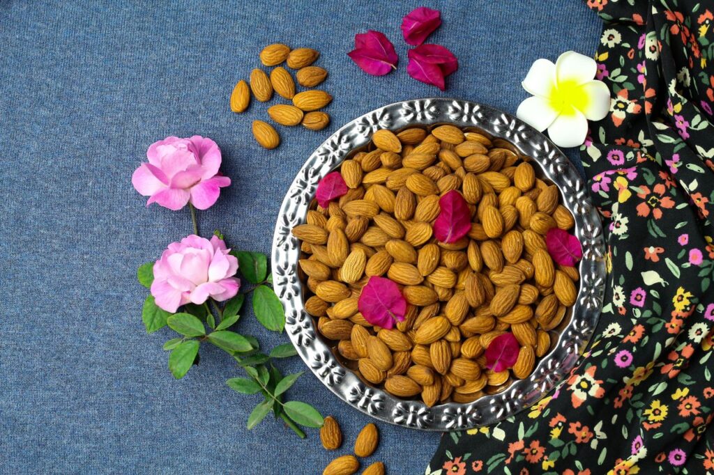 Top view of almonds and flowers artfully arranged on a denim surface. Vibrant colors enhance visual appeal.